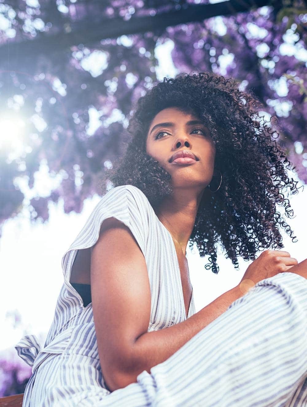 Young black woman sitting surrounded by flowers